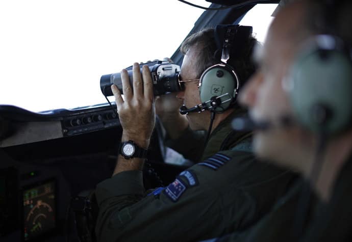 Wing Commander Shearer looks through binoculars on a Royal New Zealand Air Force P-3K2 Orion aircraft during a search for the missing Malaysian Airlines MH370 over the southern Indian Ocean