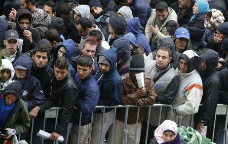 Migrants queue outside Office of Health and Social Affairs as they wait to register in Berlin